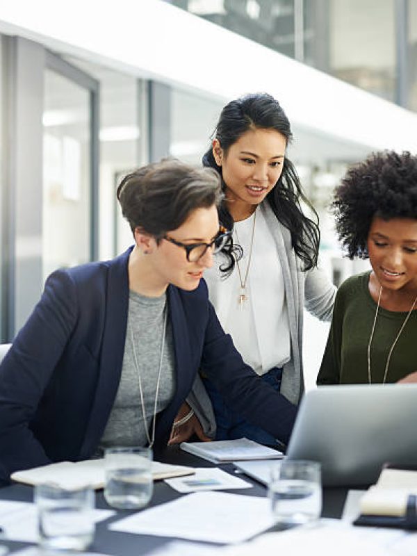 Shot of a group of businesswomen using a laptop during a meeting at work